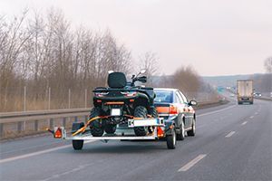 Car towing an ATV on a trailer