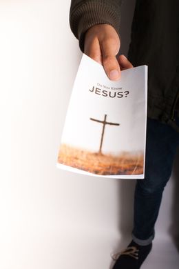Person holding a pamphlet with a cross and the question