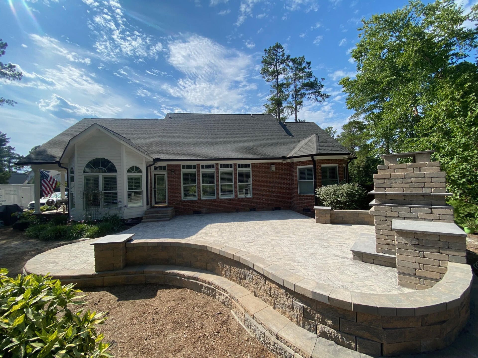 A large brick house with a patio and a fireplace in front of it.