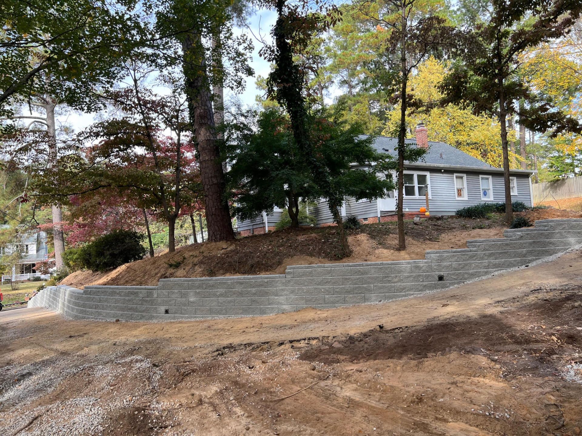 A house is sitting on top of a hill next to a concrete retaining wall.