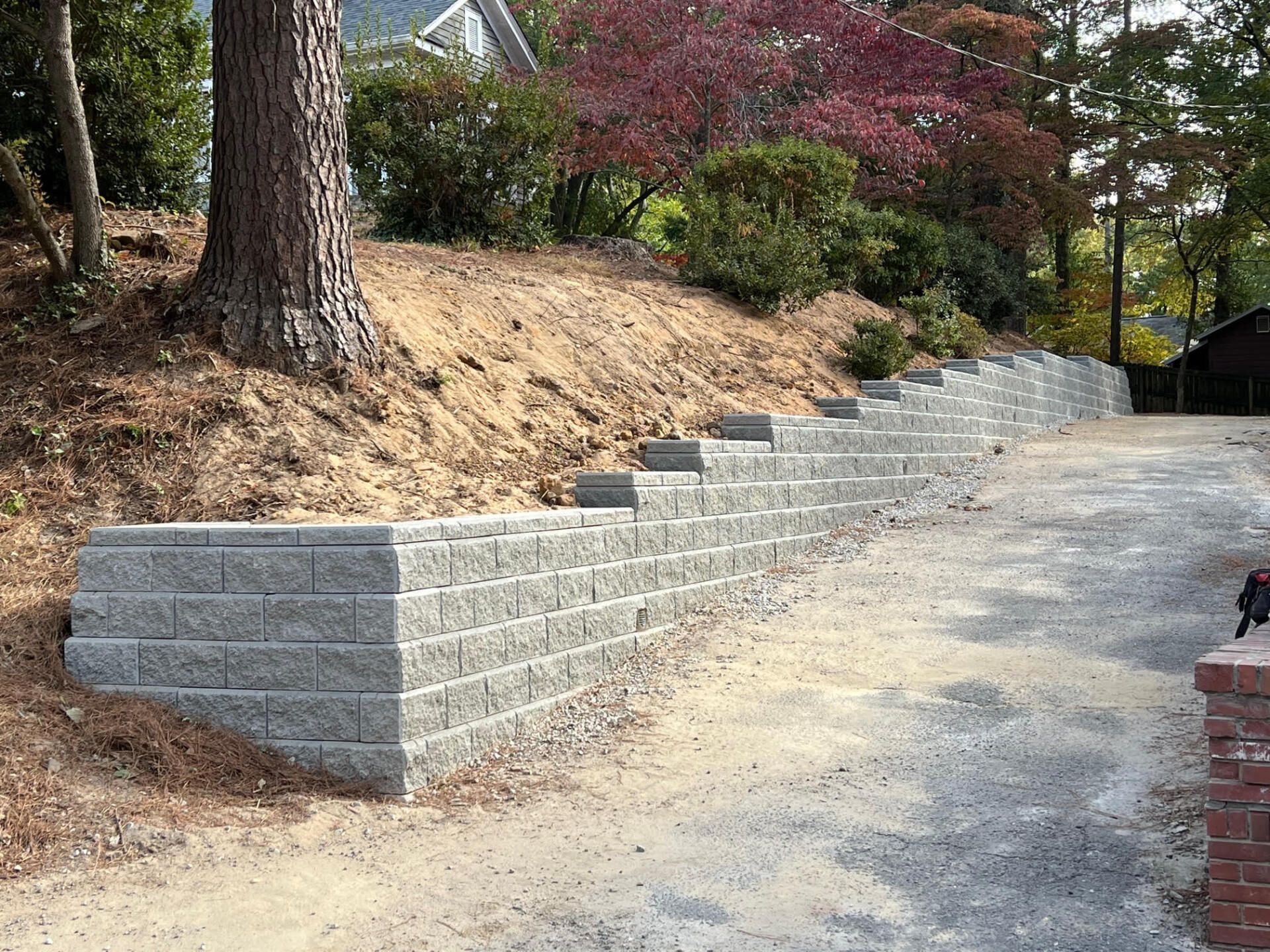 A brick wall is being built on the side of a driveway.