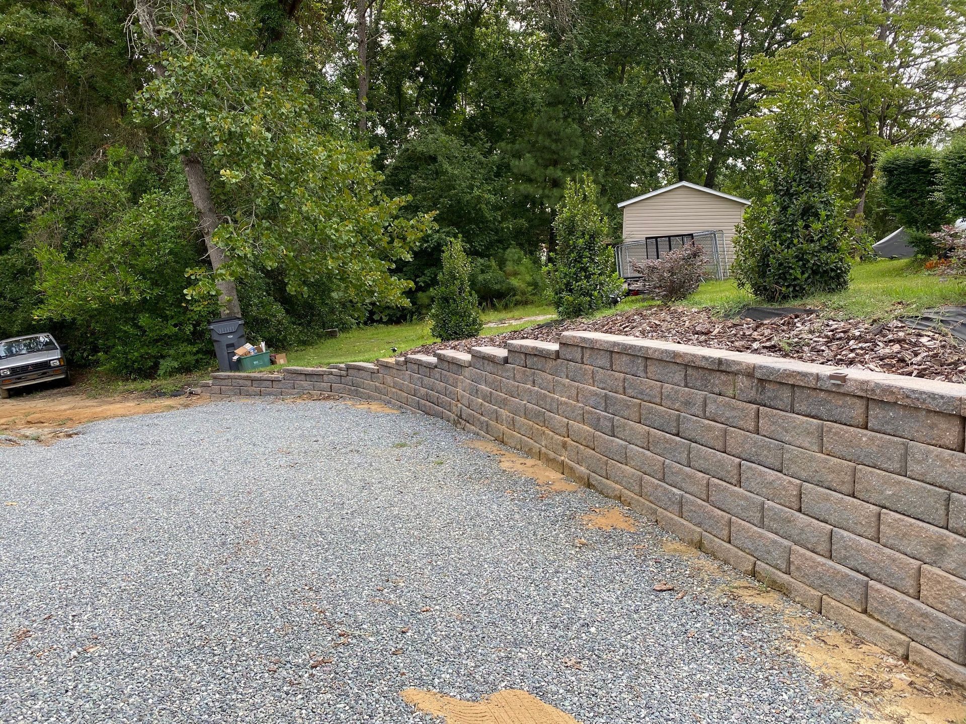 A brick wall is being built next to a gravel driveway.