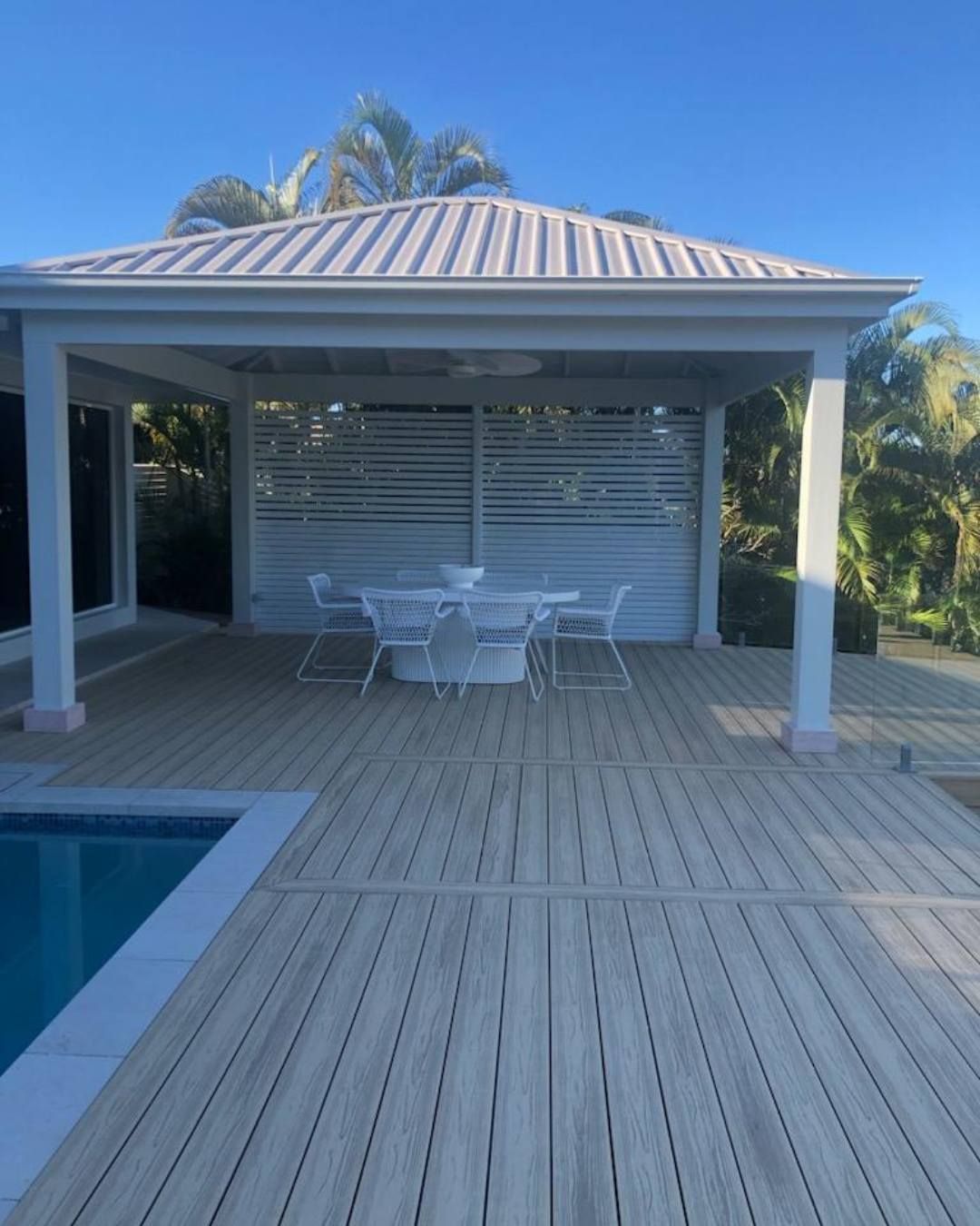 A wooden deck with a table and chairs next to a pool — Solo Reno Coatings In Gold Coast, QLD
