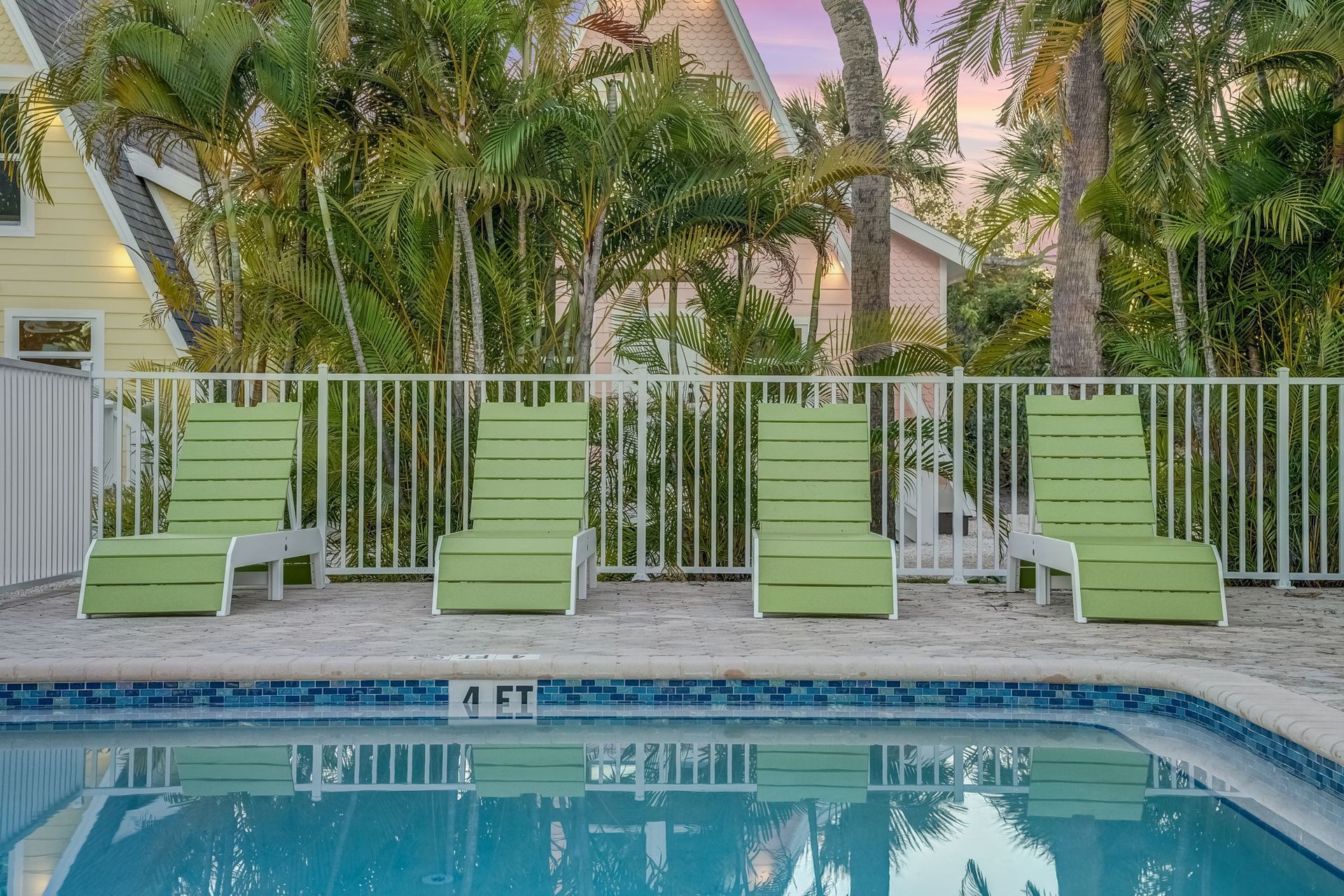 A large swimming pool surrounded by chairs and palm trees