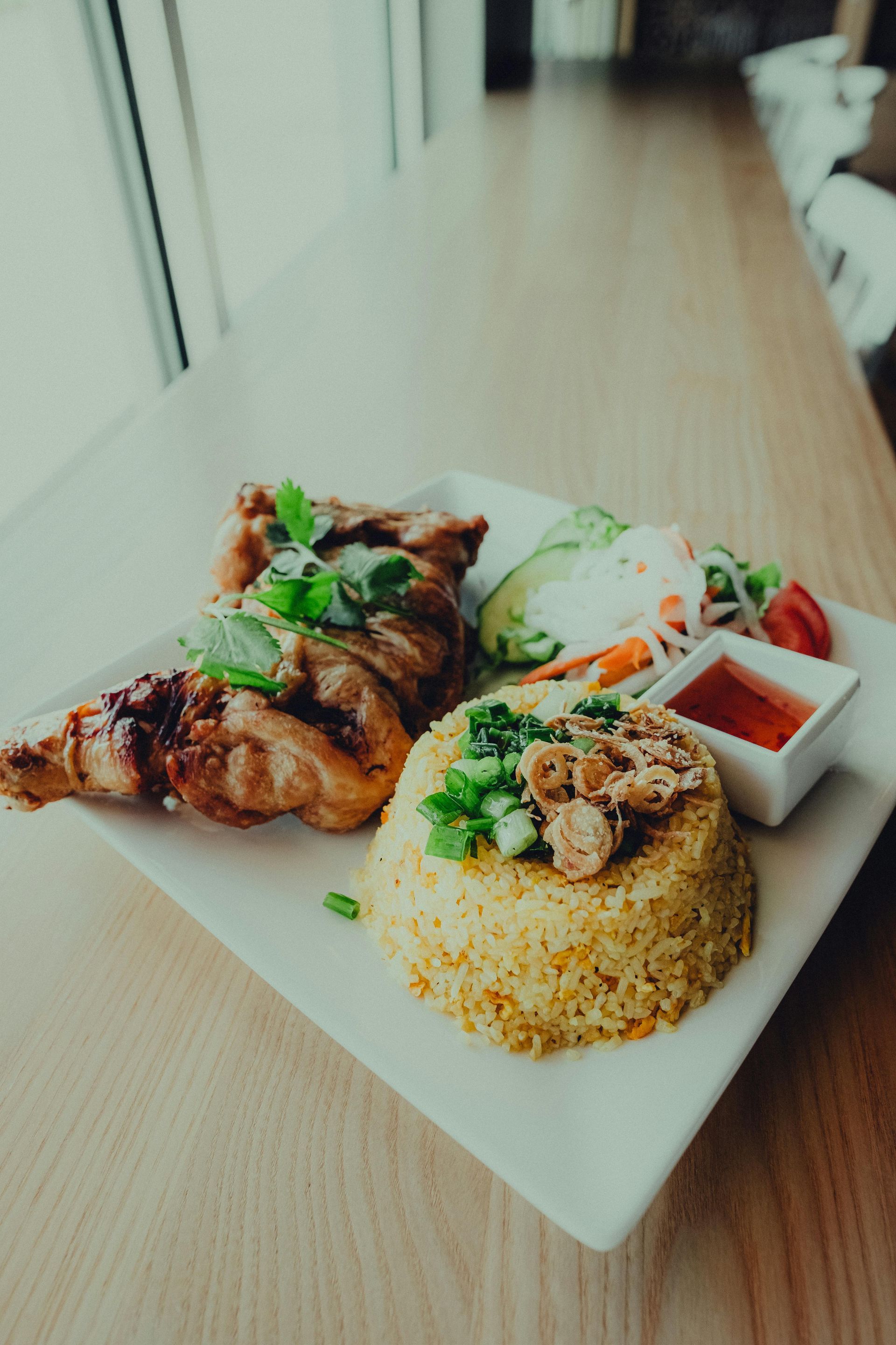 A plate of food with rice , meat and vegetables on a table.