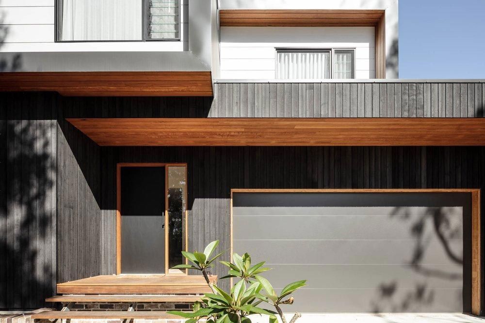 A Modern House With a Black Garage Door and a Wooden Porch — DeBu Studios In Russell Vale, NSW