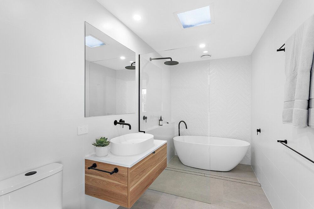 A Bathroom With a Bathtub, Sink, Mirror and Toilet — DeBu Studios In Russell Vale, NSW