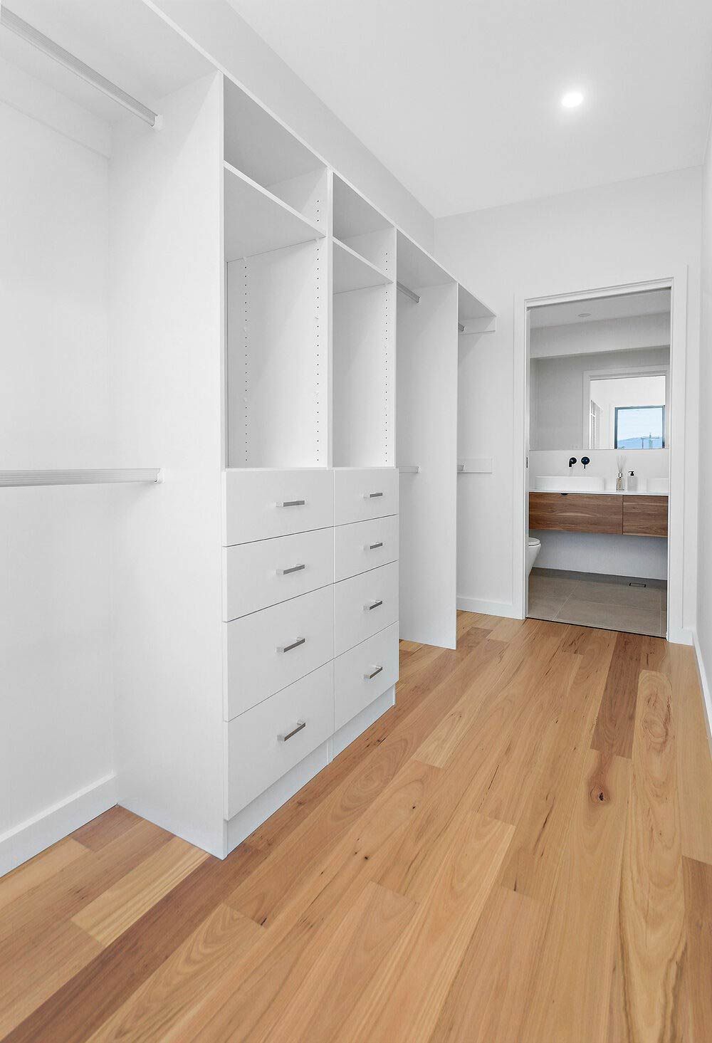 A Walk in Closet With Wooden Floors and White Cabinets — DeBu Studios In Russell Vale, NSW