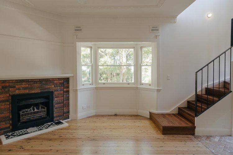 An Empty Living Room With a Fireplace and Stairs — DeBu Studios In Russell Vale, NSW