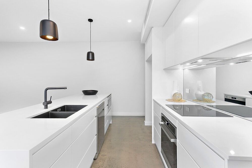 A Kitchen With White Cabinets, Black Appliances, a Sink and a Stove — DeBu Studios In Russell Vale, NSW