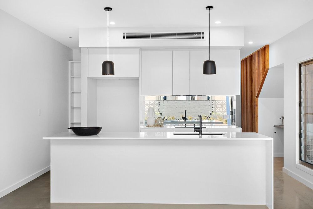 A Kitchen With White Cabinets and a Large Island in the Middle — DeBu Studios In Russell Vale, NSW