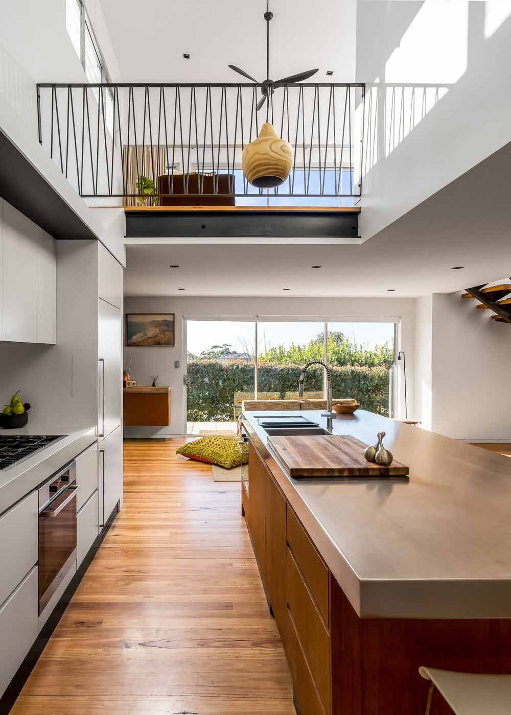 A Kitchen With a Large Island in the Middle of It and a Balcony Above It — DeBu Studios In Russell Vale, NSW