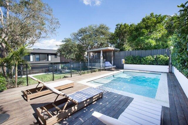 A Large Swimming Pool is Surrounded by Trees — DeBu Studios In Russell Vale, NSW