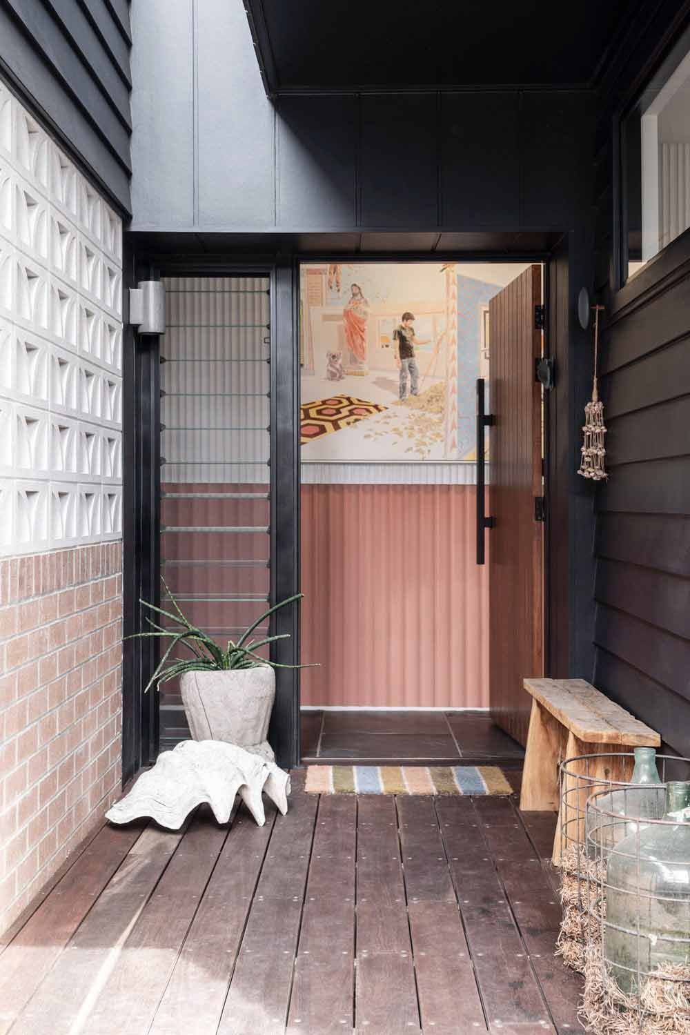 A Wooden Porch With a Bench and a Potted Plant in Front of a Door — DeBu Studios In Russell Vale, NSW