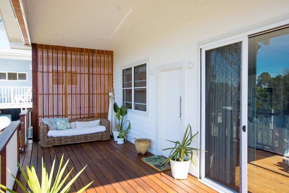 A Balcony With a Couch, Potted Plants and a Sliding Glass Door — DeBu Studios In Russell Vale, NSW
