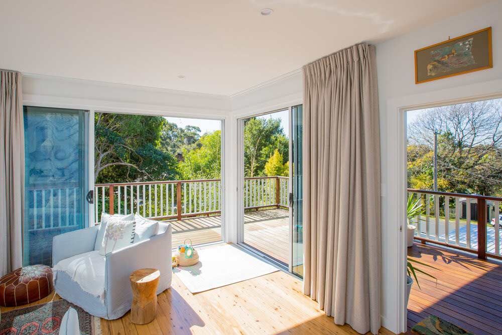 A Living Room With a Couch, Chair, Table and Sliding Glass Doors — DeBu Studios In Russell Vale, NSW
