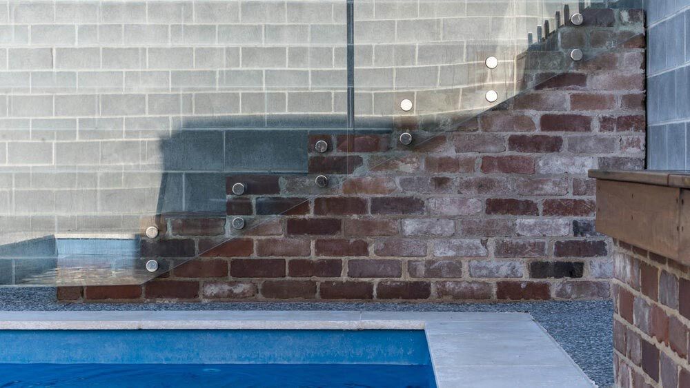 A Swimming Pool With a Brick Wall and Stairs Behind It — DeBu Studios In Russell Vale, NSW