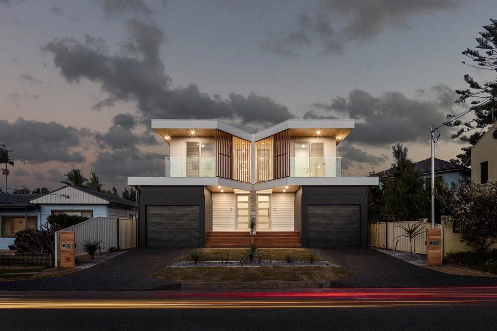 A Modern House With Two Garages is Sitting on the Corner of a Street — DeBu Studios In Russell Vale, NSW
