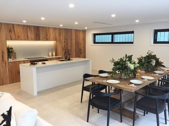 A Dining Room With a Table and Chairs and a Kitchen in the Background — DeBu Studios In Russell Vale, NSW