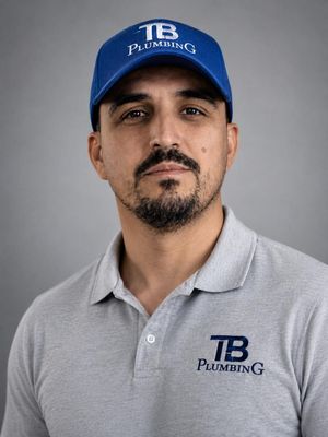 A man in a blue TB Plumbing cap and gray TB Plumbing polo shirt