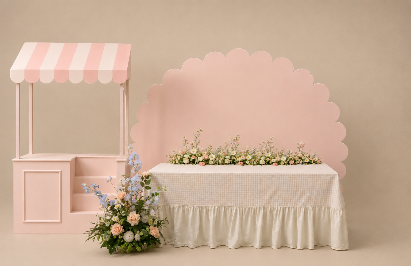 Mesa de doces em tons pastel rosa com carrinho de flores, painel de fundo ondulado e mesa coberta com tecido creme.