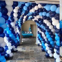 Blue, white, and navy balloon arch tunnel in a decorated indoor event space