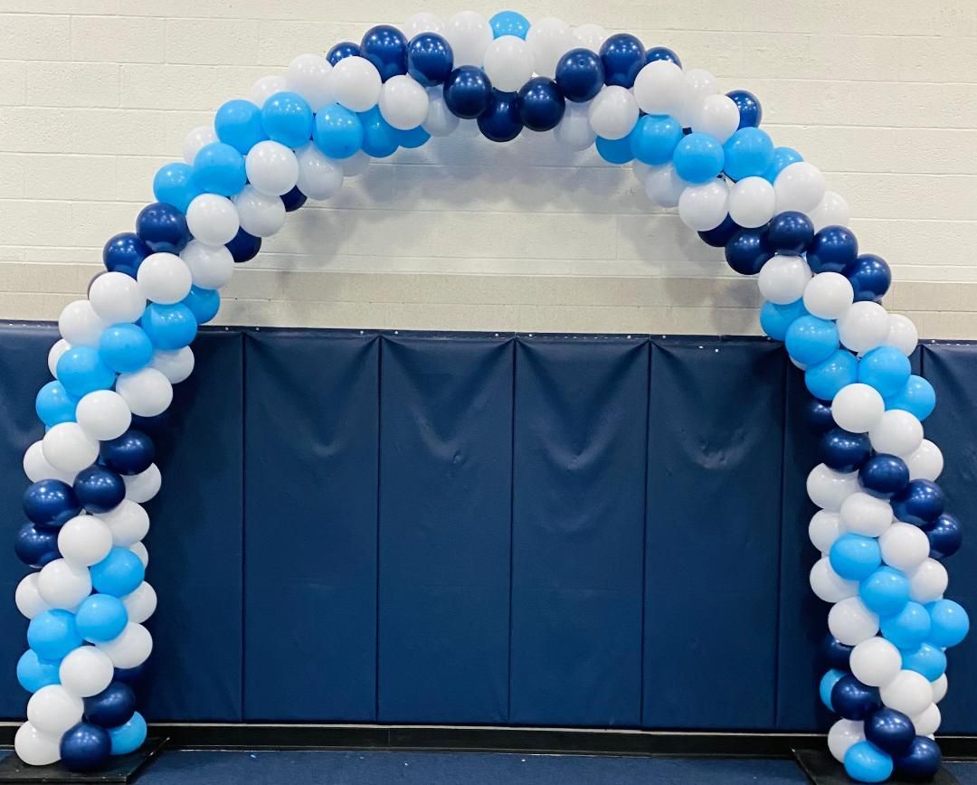Blue and white balloon arch framing a blue-draped stage in a gymnasium