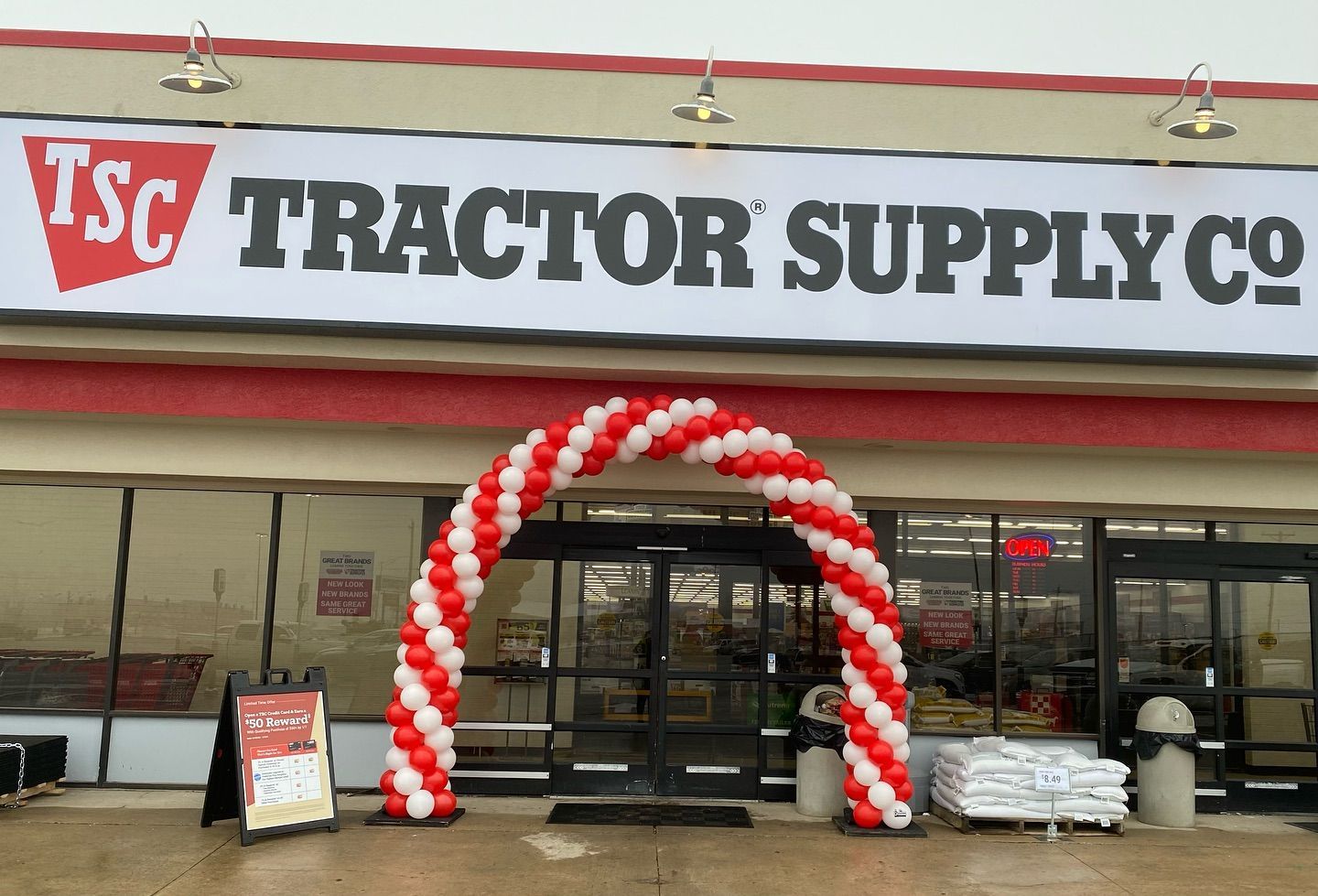 Tractor Supply Co store entrance with red and white balloon arch and wet pavement
