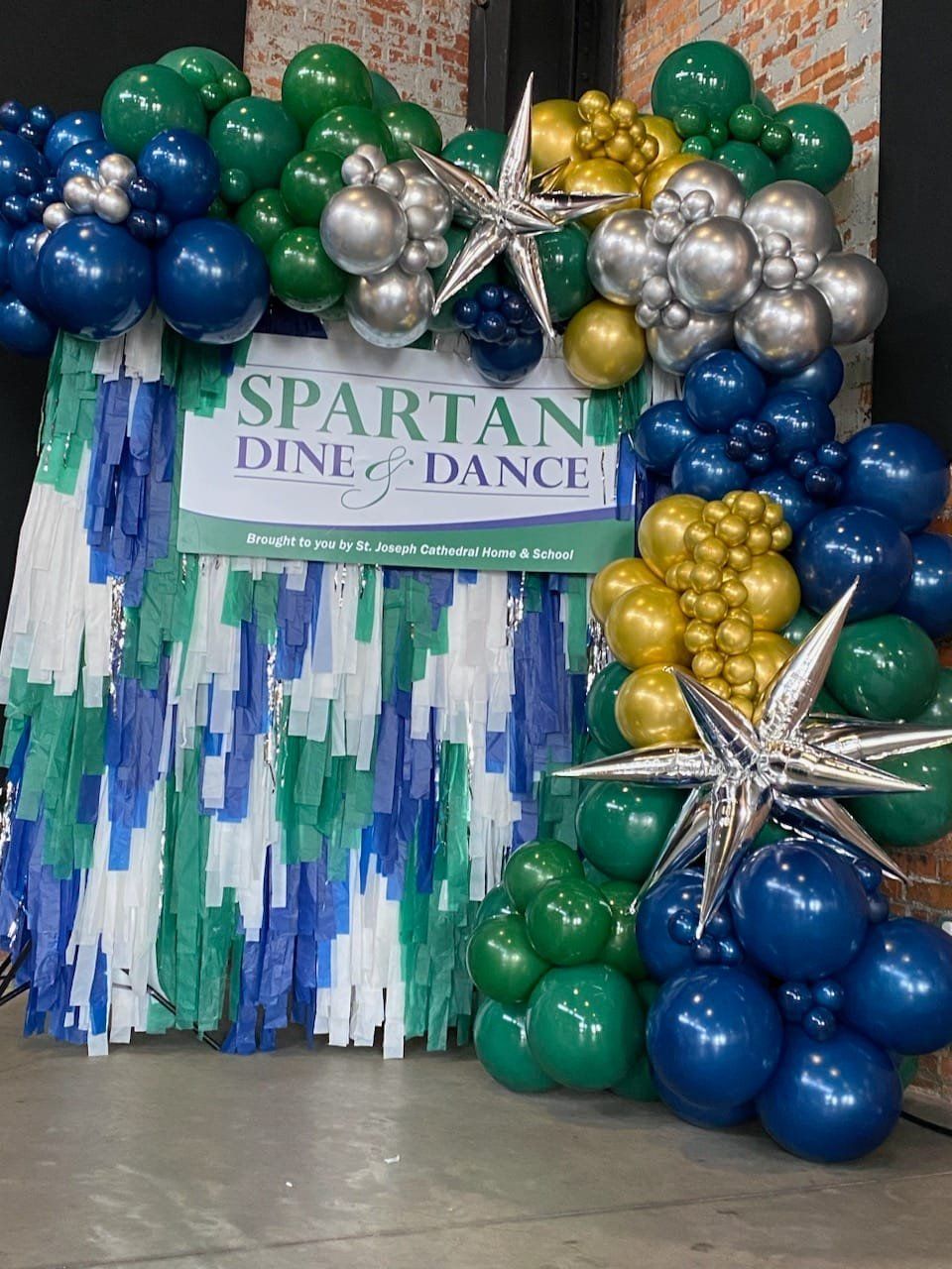 Balloon arch backdrop in green, blue, silver, and gold for Spartan Dine and Dance event