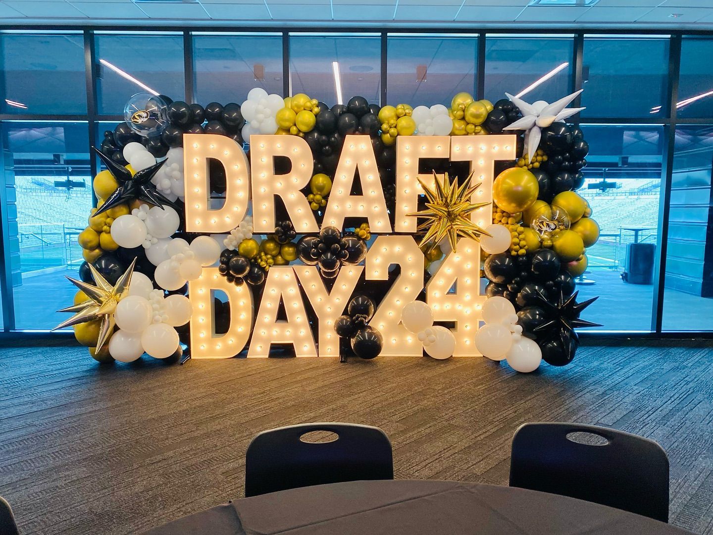“DRAFT DAY” balloon display with black, gold, and white decorations in a bright indoor venue