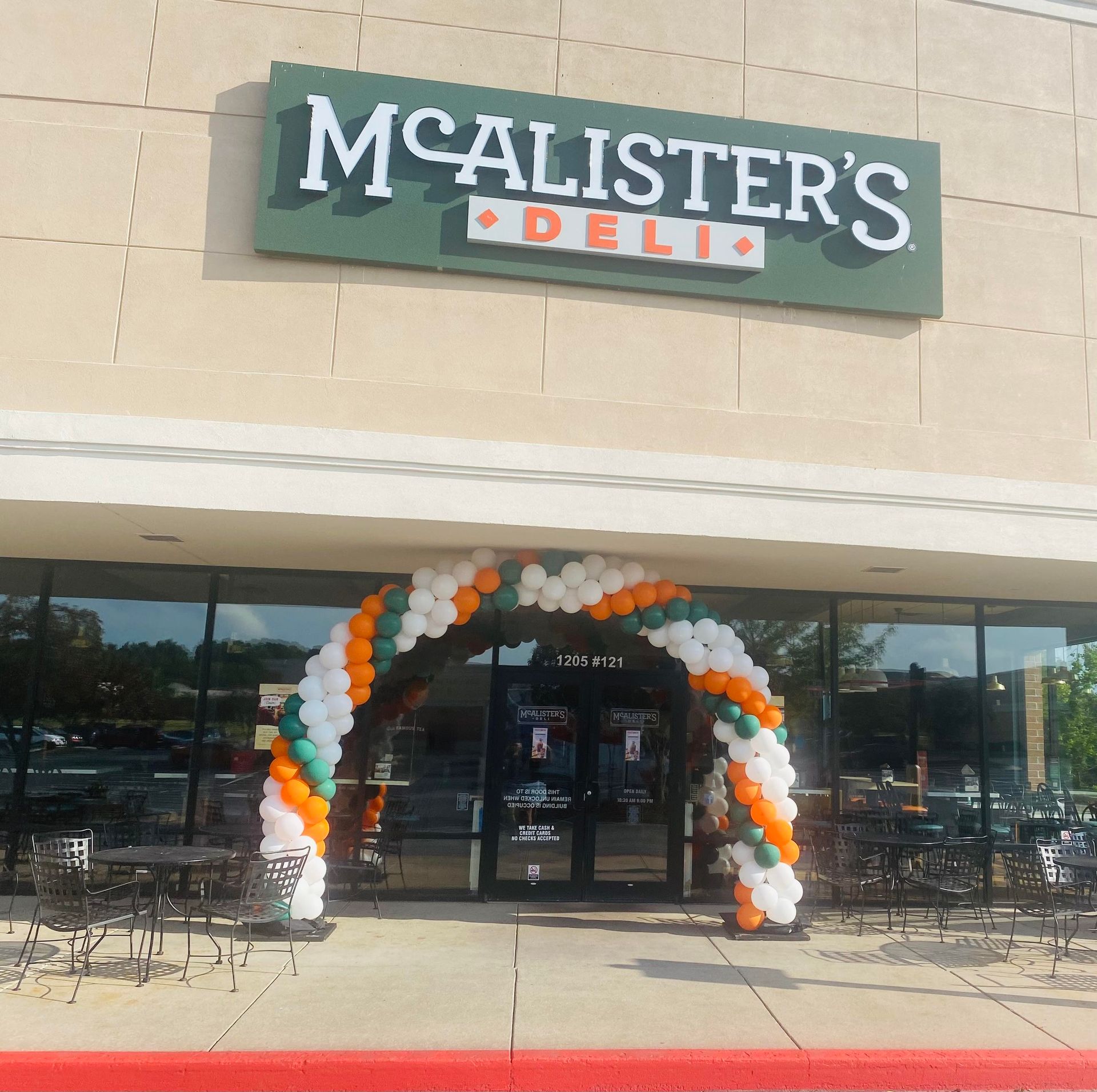 McAlister’s Deli storefront with orange, white, and green balloon arch by the entrance