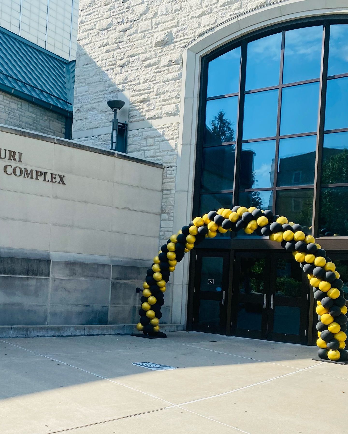 Entrance to a stone building with a black-and-yellow balloon arch over the doorway