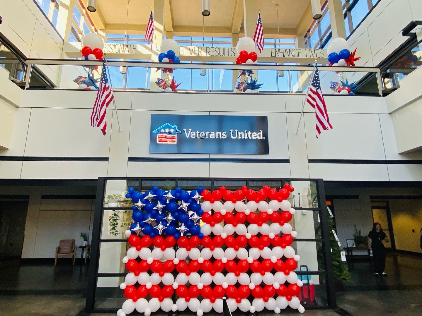 Veterans United lobby decorated with red, white, and blue balloons and American flags on upper and lower levels