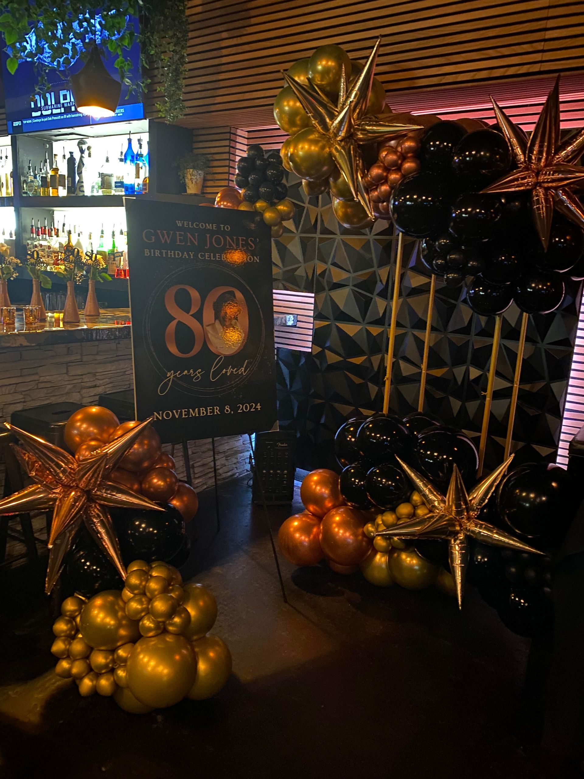 Gold star and balloon decorations around a “80” sign at a festive event display.