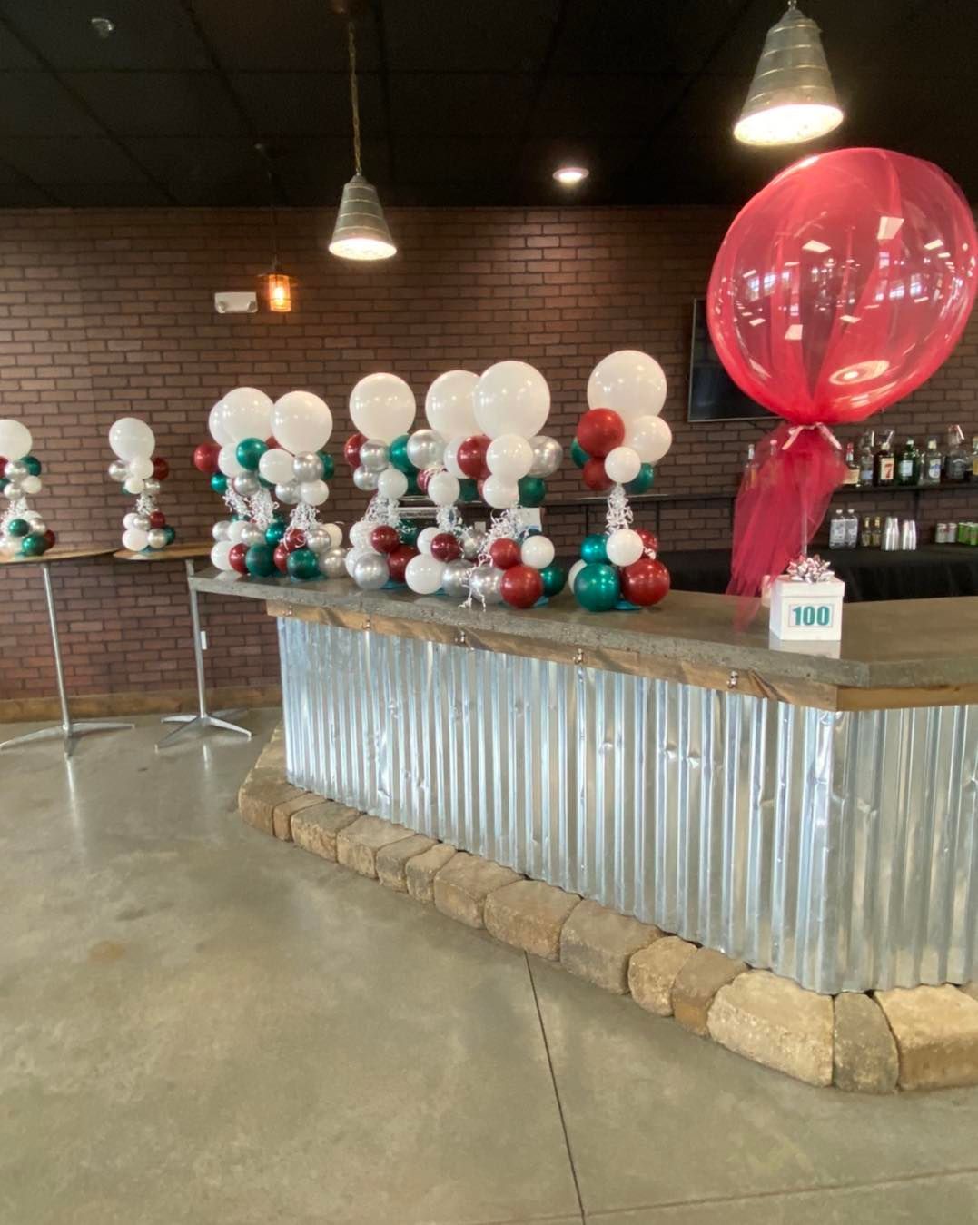 Decorated dessert table with white and red balloon displays in a rustic indoor event space
