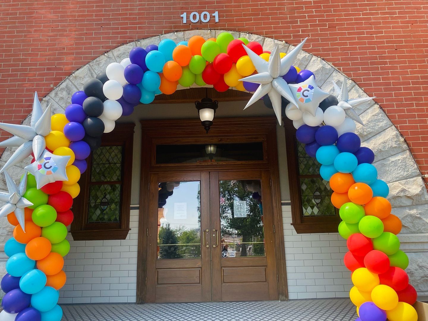 Balloon arch in rainbow colors decorating a building entrance with star balloons