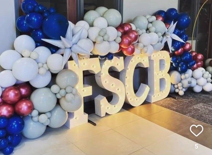 Balloon backdrop with gold “ESCB” letters in blue, white, and pink tones