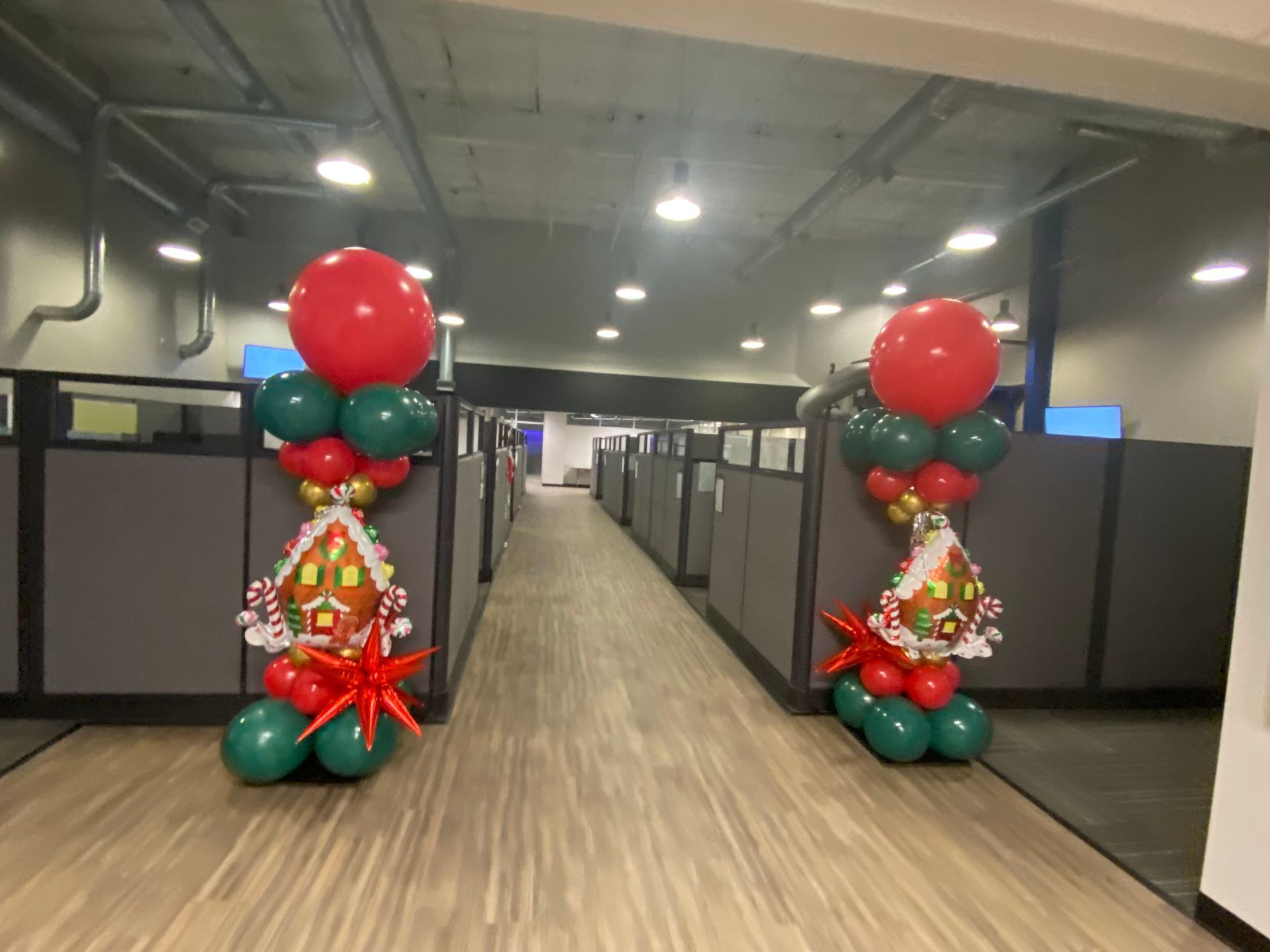 Office hallway decorated with red and green balloon columns at the entrance