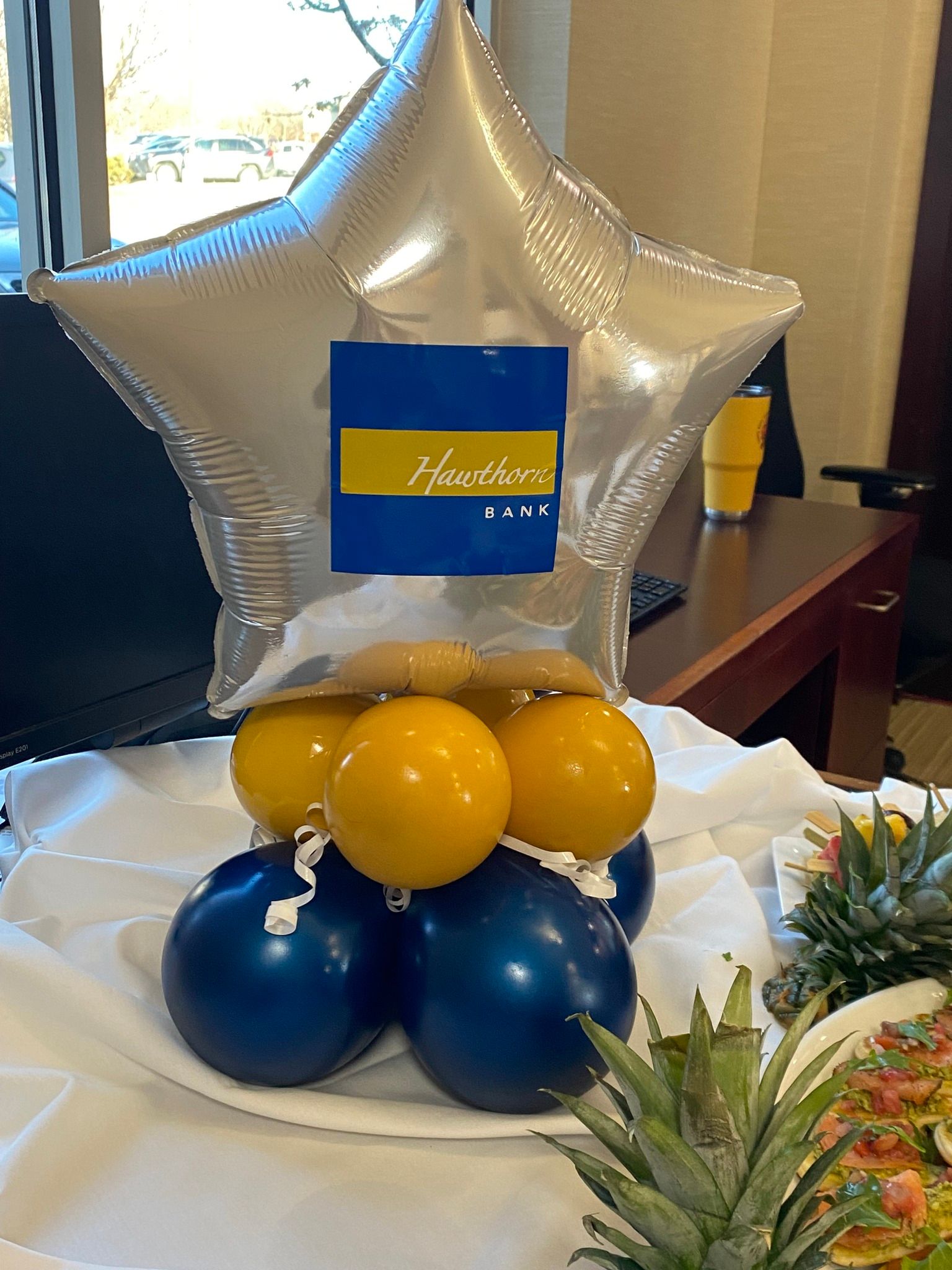 Silver star balloon with blue and gold balloons on a table, with a small sign in front
