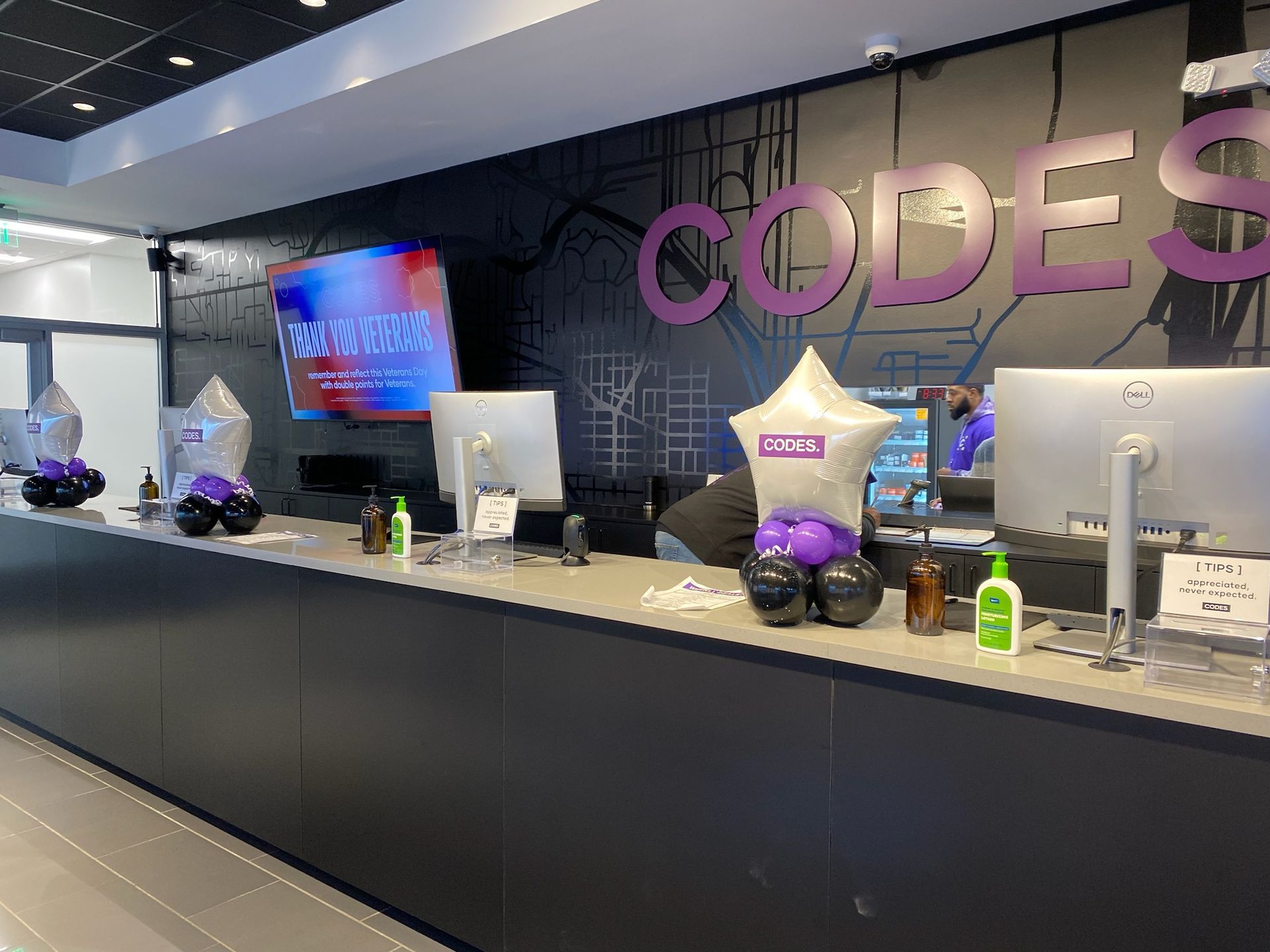 Corporate reception desk with CODES sign, monitors, and decorative items in a modern lobby