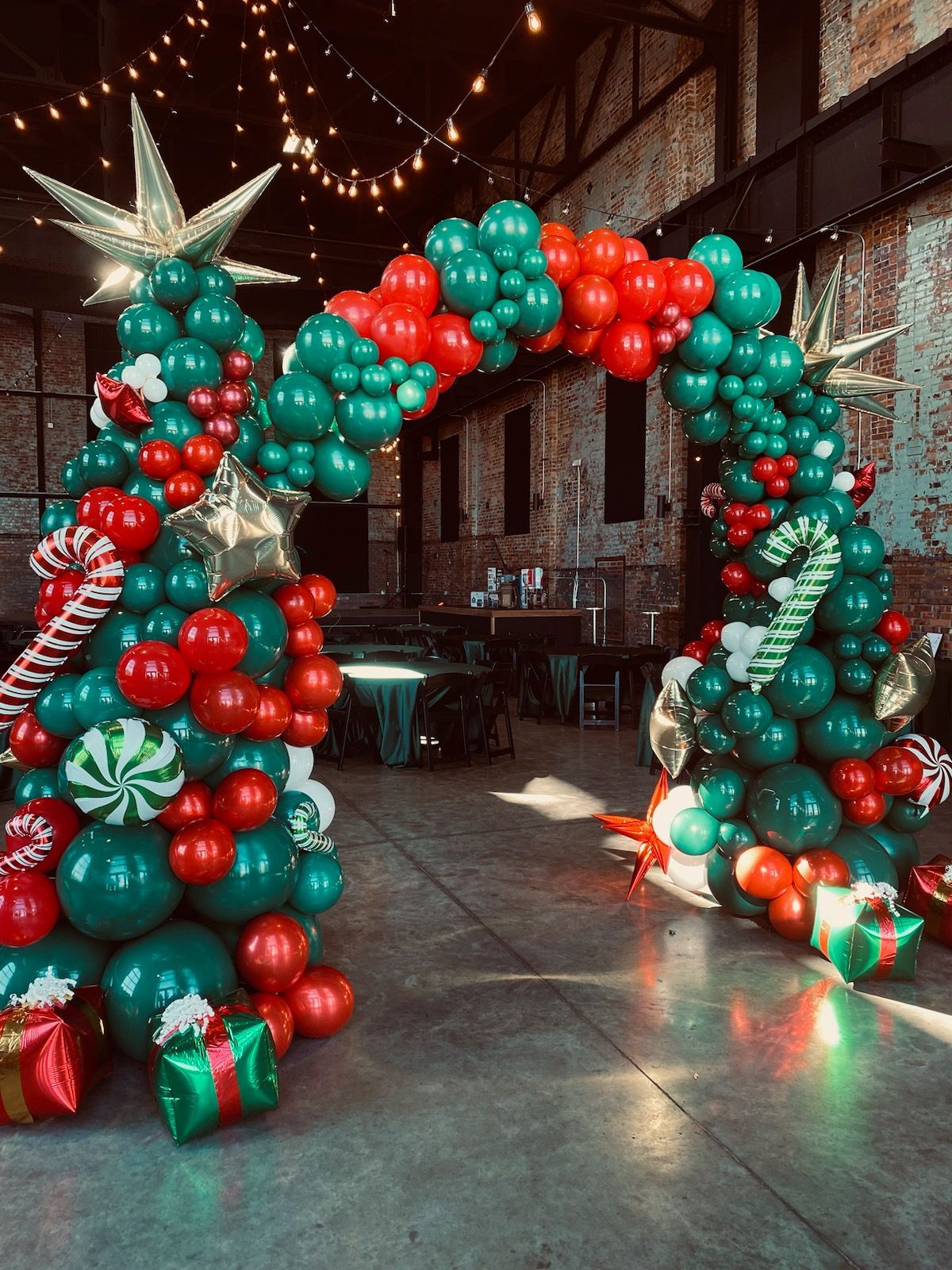 Red and teal balloon arch with a star topper in a decorated indoor event space