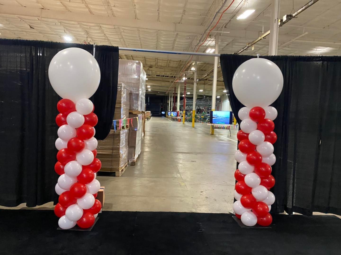 Red and white balloon columns framing an open entrance in a large indoor hall
