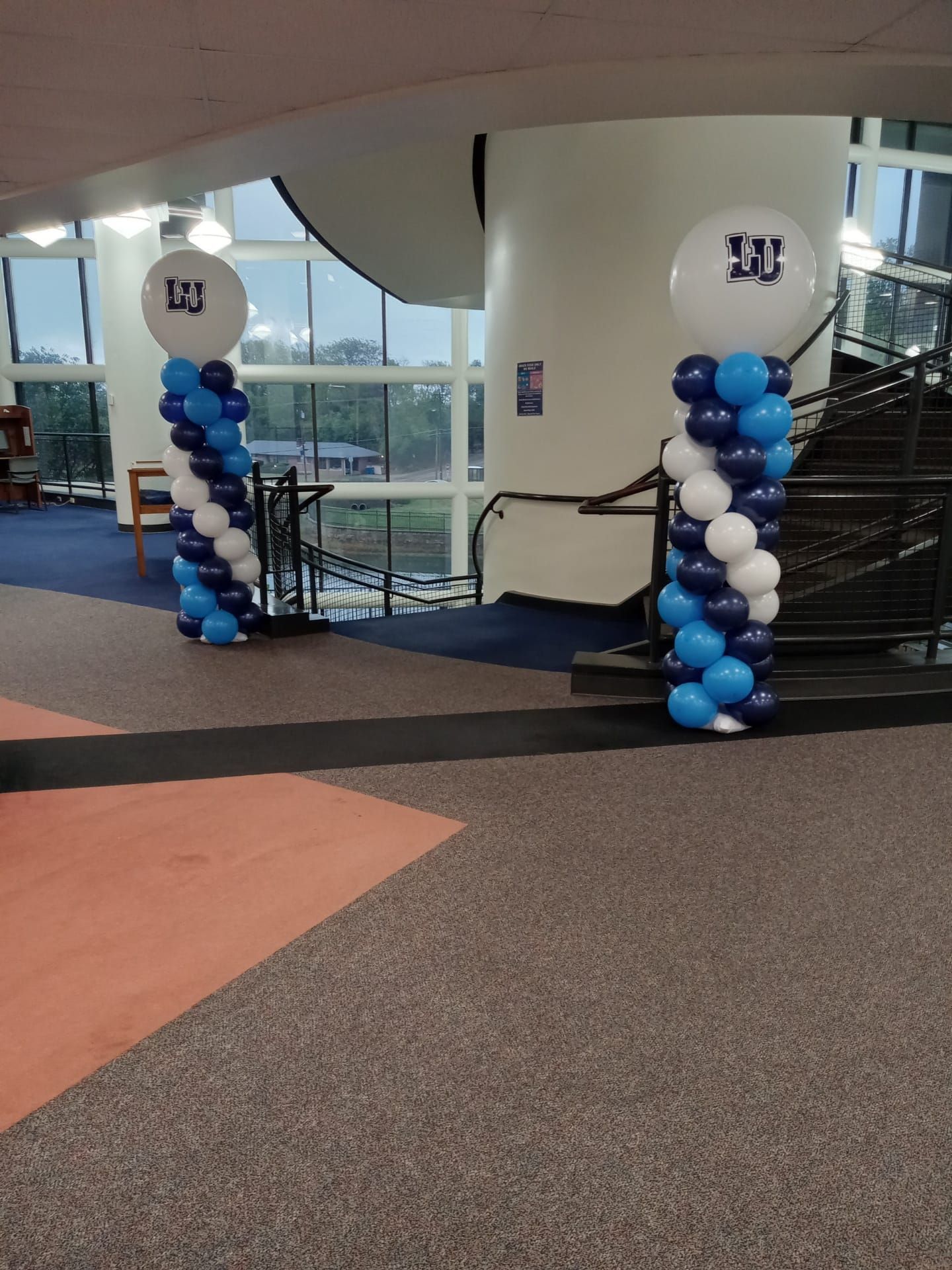 Blue and white balloon columns framing an indoor walkway near large windows