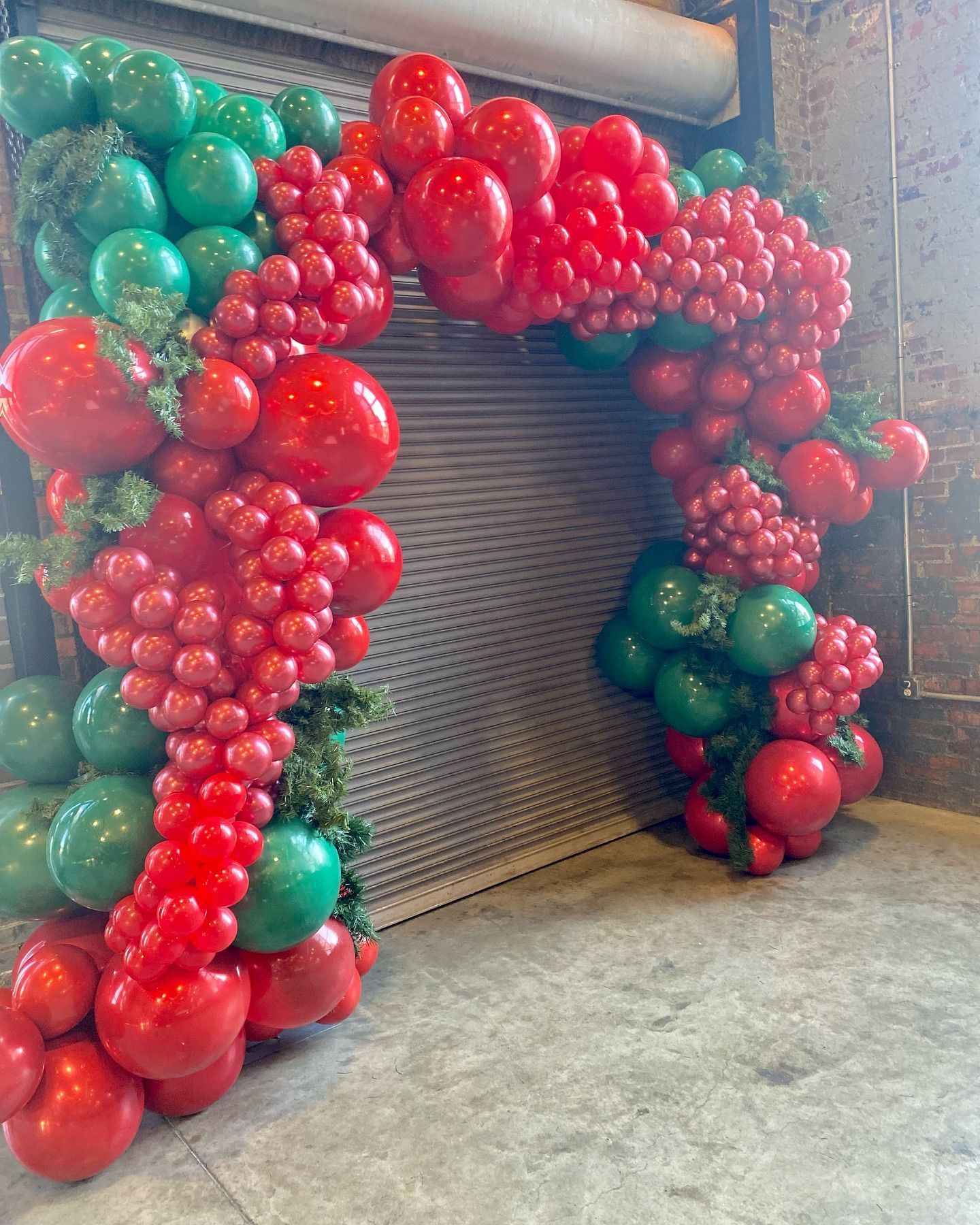 Red and green balloon arch framing a doorway in an indoor space.