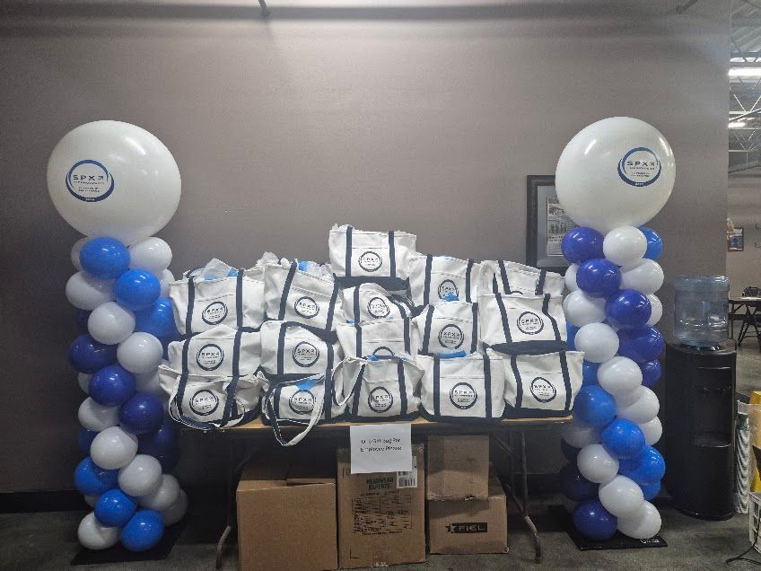 Balloon display with blue and white columns framing stacks of white bags and cardboard boxes in a room