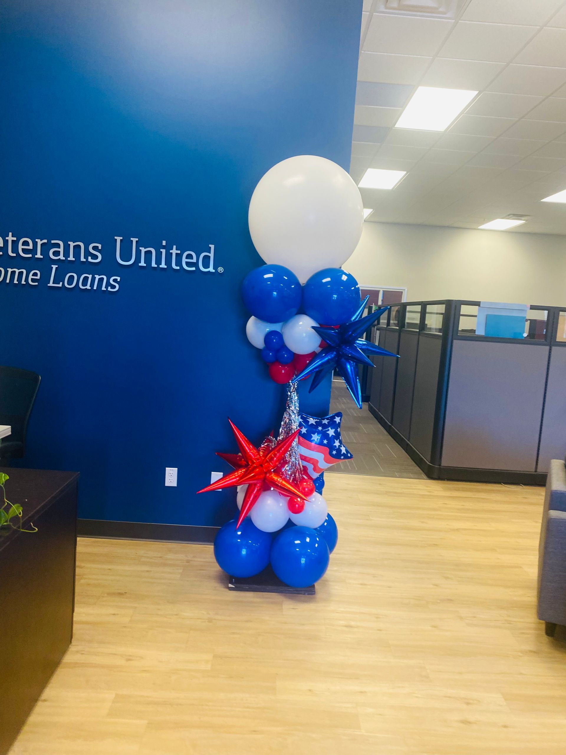 Blue, white, and red balloon column in an office lobby with a Veterans United sign.