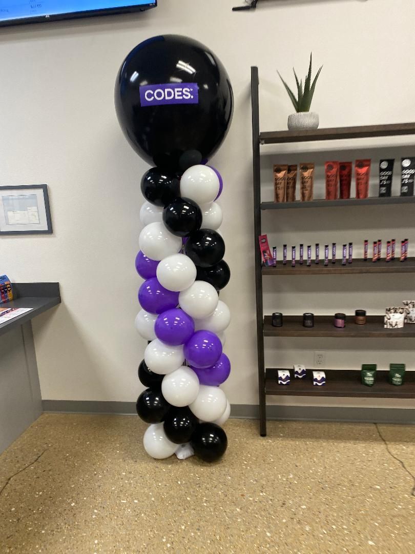 Black, white, and purple balloon column beside shelves in a store or office lobby
