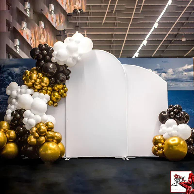 White event backdrop with black, white, and gold balloon clusters in a showroom