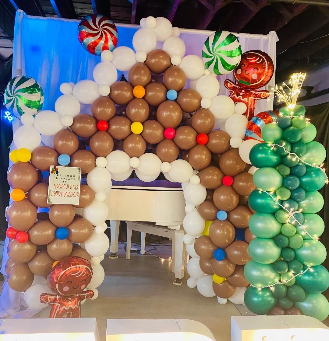 Gingerbread house balloon display with candy cane and lollipop decorations, framing a doorway indoors