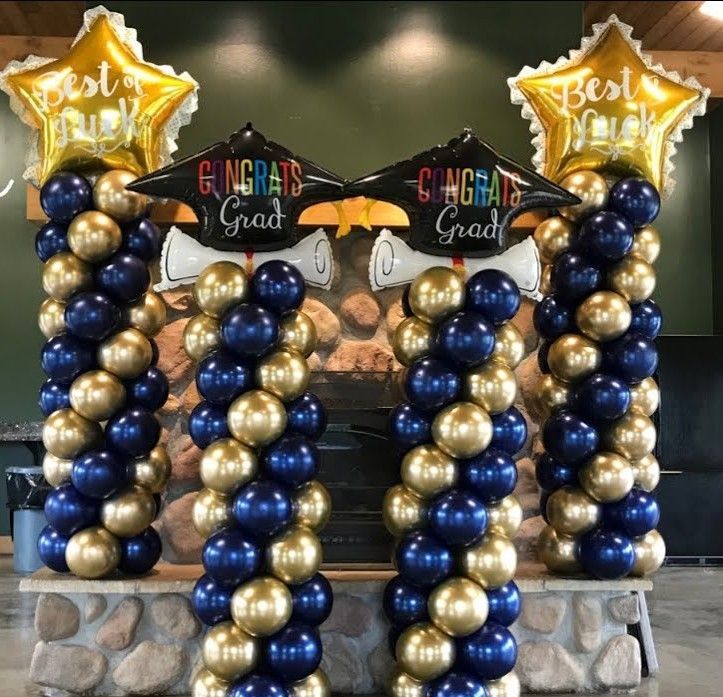 Three blue and gold balloon columns with gold star toppers and graduation signs reading “Congrats Grad” and “Best”